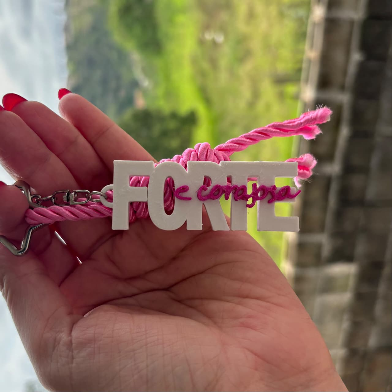 Chaveiro real da campanha: letras brancas, inscrição Forte e corajosa e cordão rosa